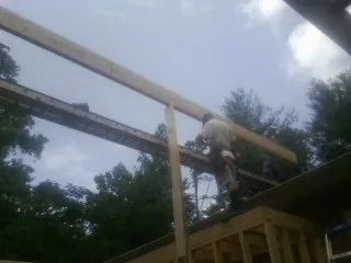 Carpenter setting a ridge beam over a new addition frame — Ice Dam Removal by Roofing Brothers in Daykin