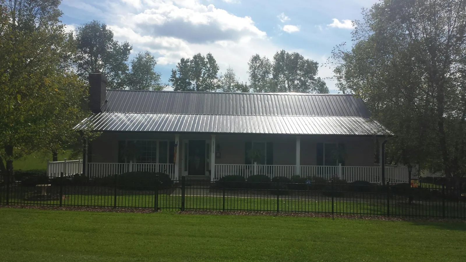 Gray metal roof on a brick ranch with a full width front porch — Gutter Guard Installation work by our crew in Daykin
