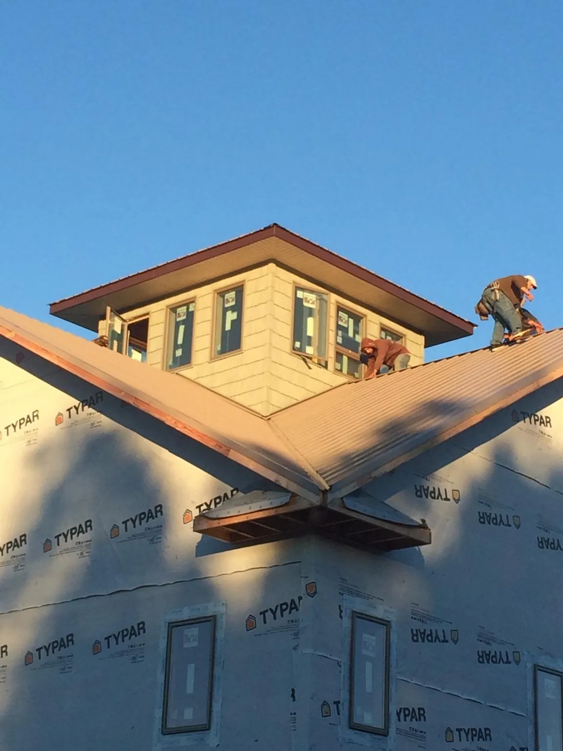 Roofers working around a rooftop cupola on a new metal roof at sunset — Roof Waterproofing in Daykin by Roofing Brothers
